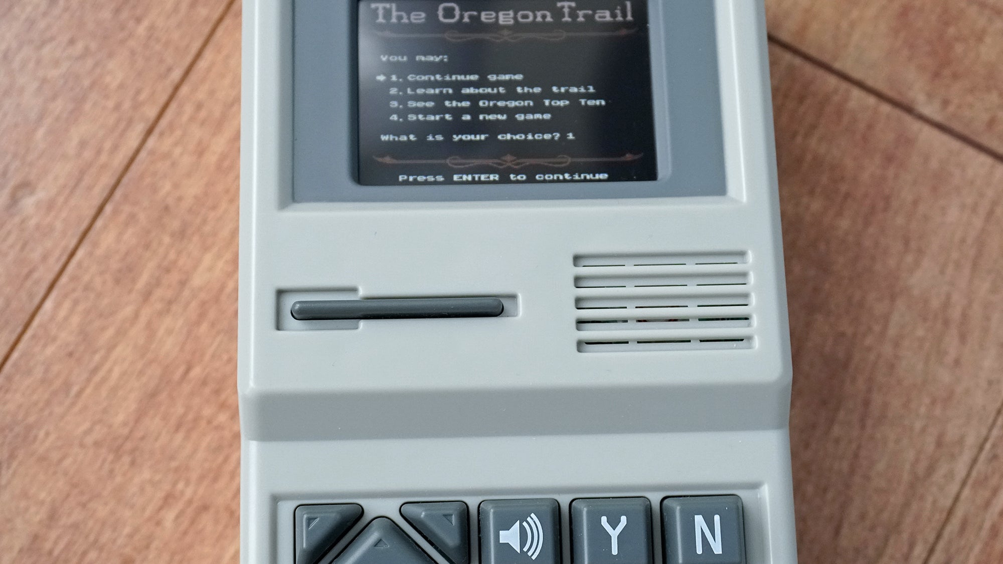 The handheld is designed to look like a miniature version of the classic Apple II person computer, including a semi-functional floppy disk power button.