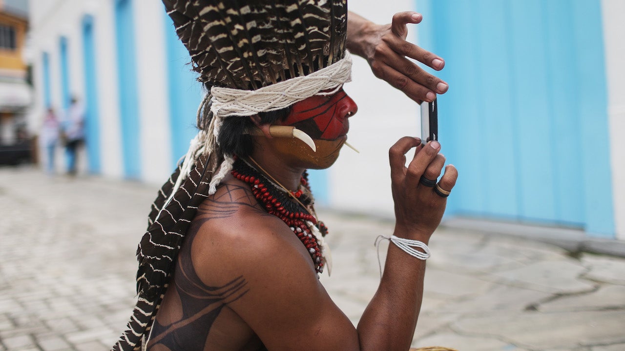 An indigenous tribe member takes a photo of another tribe member on a phone following a protest march for indigenous territorial rights on November 11, 2015 in Angra dos Reis, Brazil.