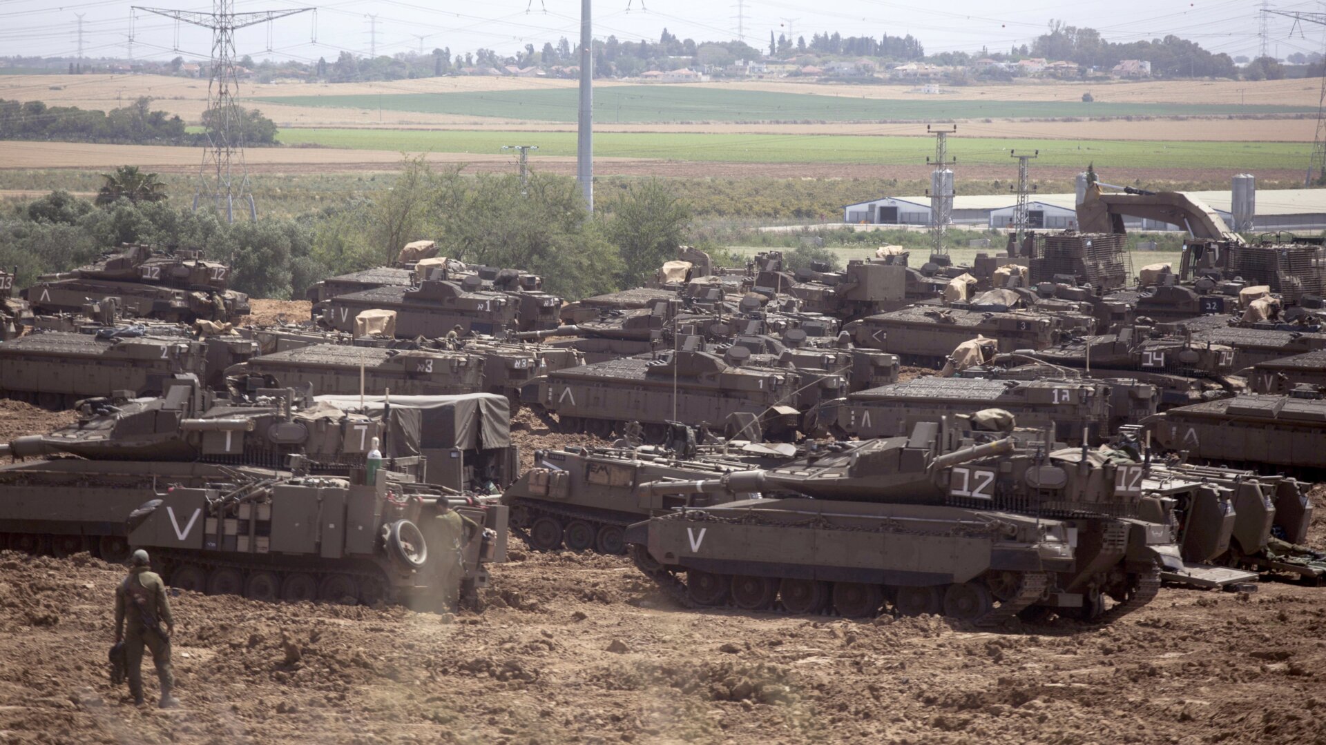 Israeli soldiers walks in front of a Merkava tanks, stationed near the border with the Gaza Strip on May 6, 2019 in Mavkim, Israel.