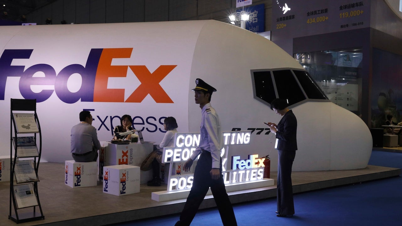 A man dressed as a pilot walks past the FedEx booth during the China International Import Expo in Shanghai on November 5, 2018