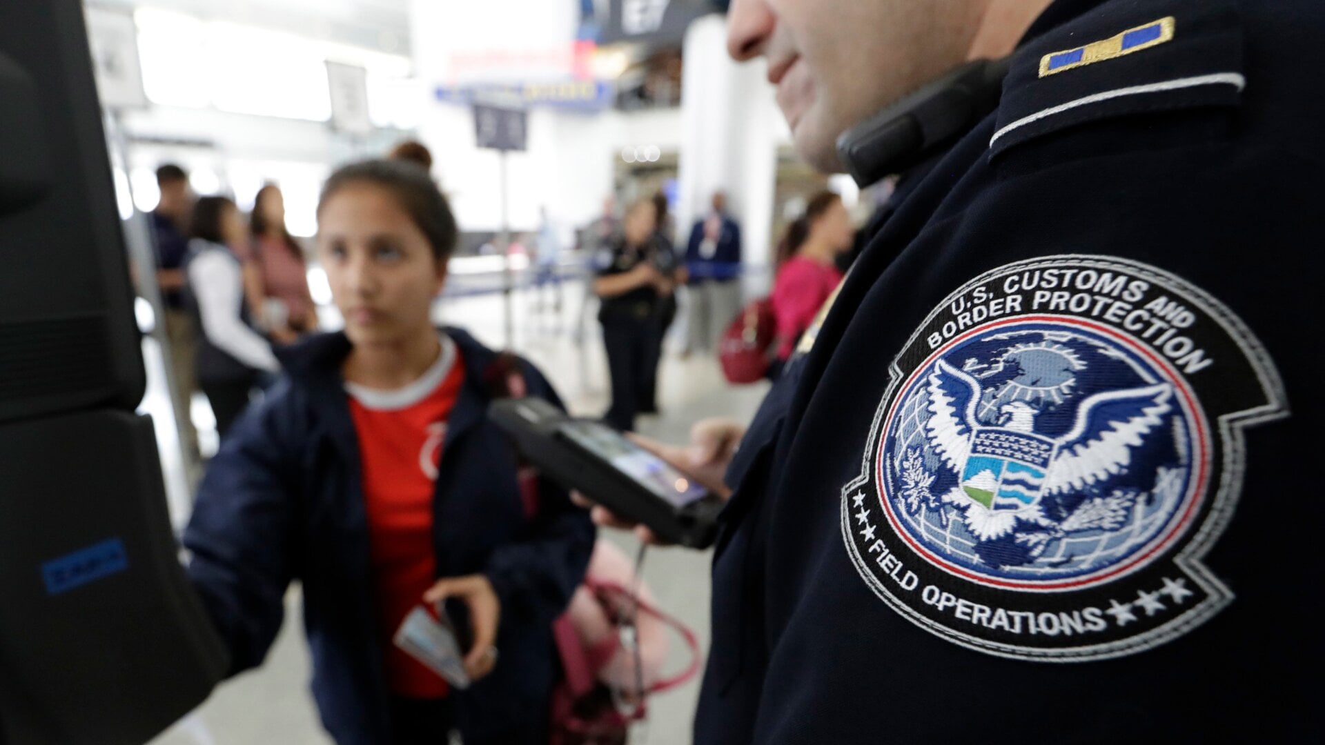 A U.S. Customs and Border Protection officer helps a passenger navigate  facial recognition kiosks at a United Airlines gate before boarding a flight to Tokyo, at George Bush Intercontinental Airport, in Houston.