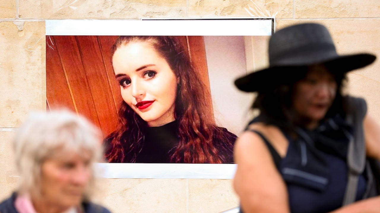 Members of the public walk past a photo of Grace Millane during a vigil at Civic Square on December 12, 2018 in Wellington, New Zealand.