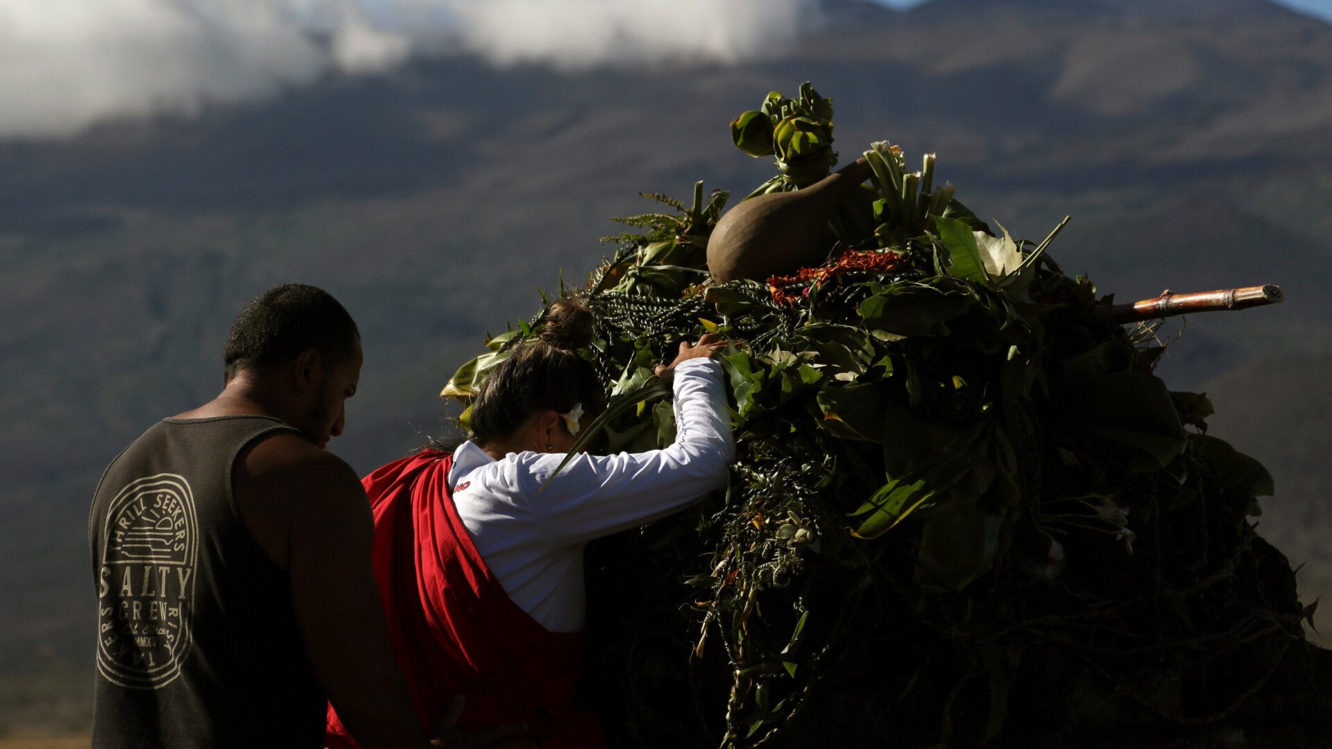 Native Hawaiian activists pray at the base of Hawaii’s Mauna Kea in background.
