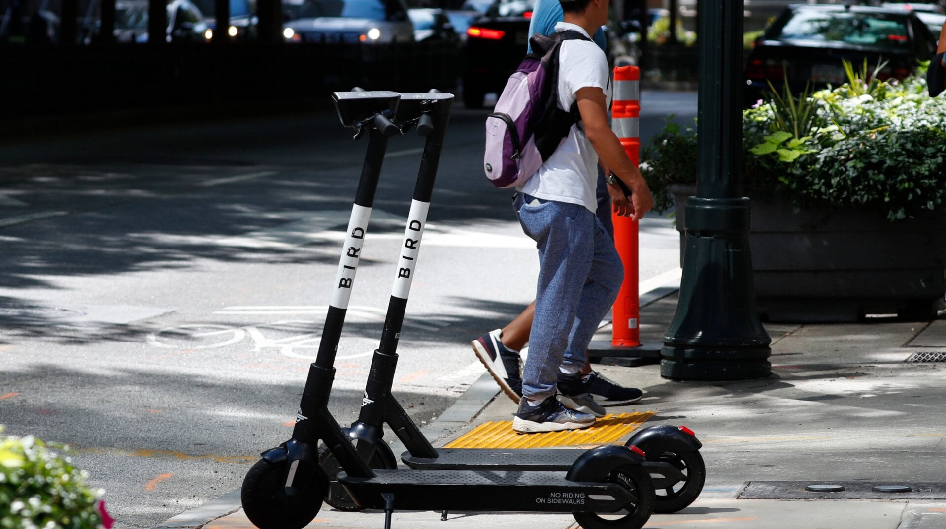 Pedestrians walk past electric scooters Thursday, Aug. 8, 2019, in Atlanta.