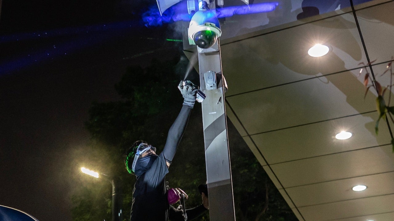 A pro-democracy protester sprays paint over a CCTV camera outside the Central Government Complex on September 28, 2019 in Hong Kong