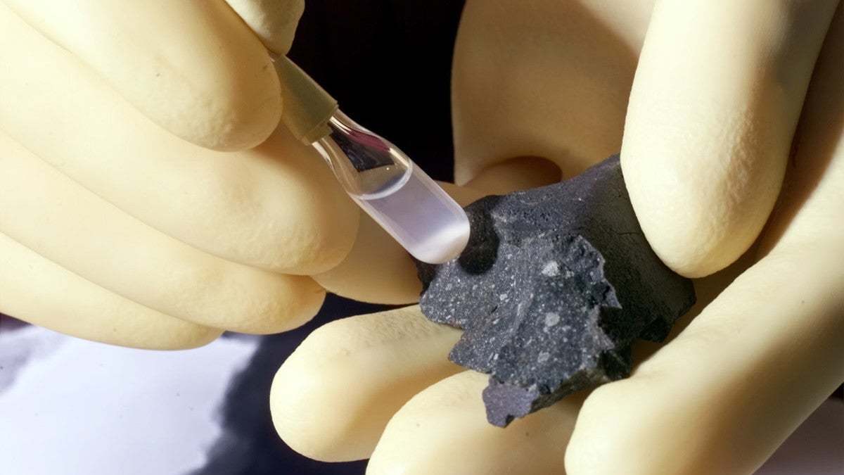 A scientist analyzing a fragment of the Murchison meteorite.