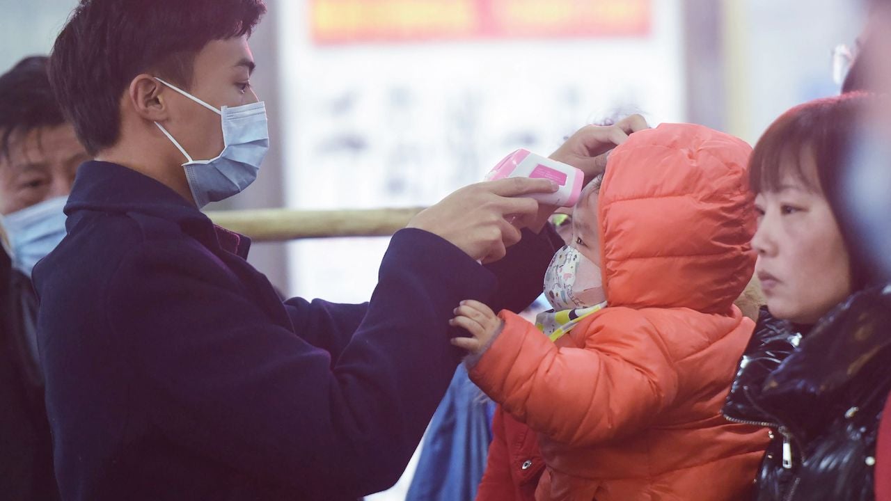 A staff member checks the body temperature of a child after a train from Wuhan arrived at Hangzhou Railway Station in Hangzhou, China.
