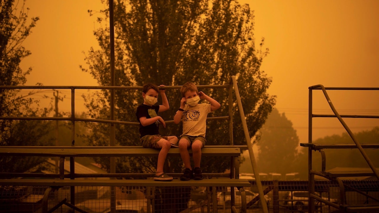 Children wear masks as they play near the town of Bega, Australia where people are camping after being evacuated from nearby sites affected by bushfires on December 31, 2019.