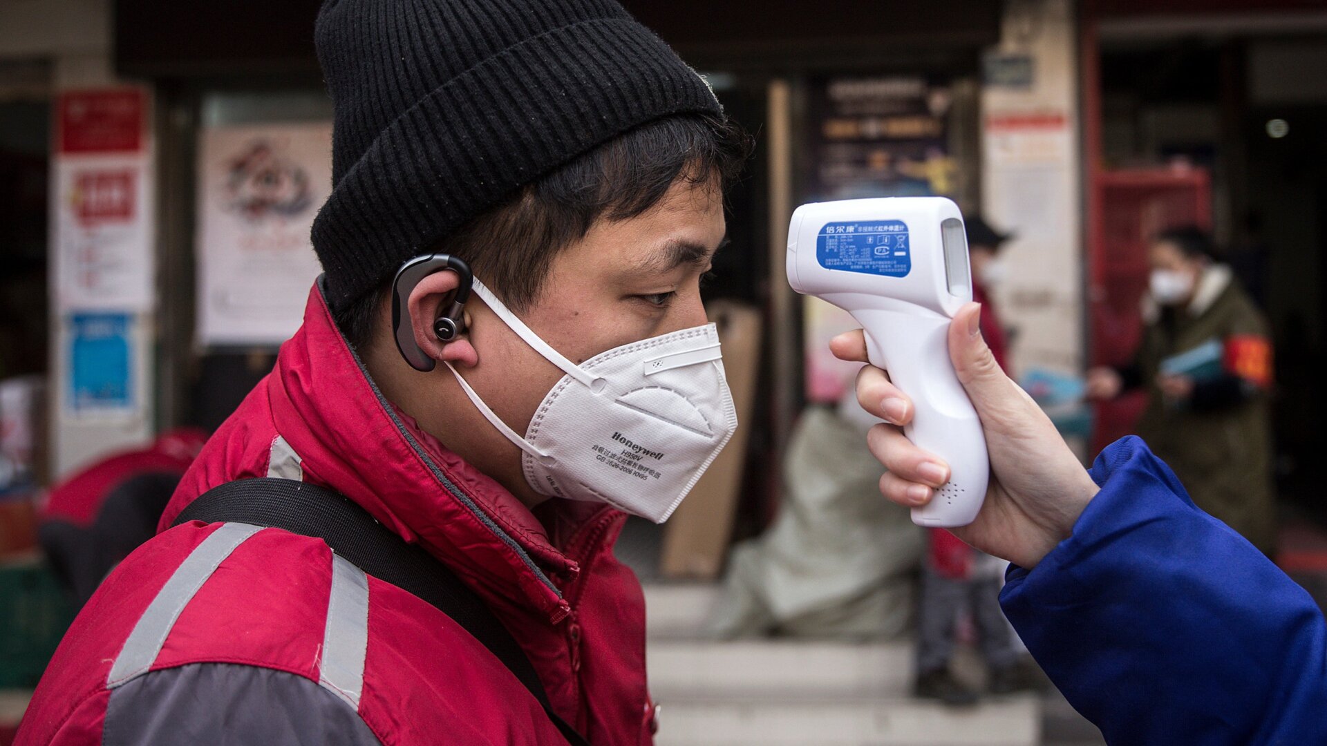 A community worker checks the temperature of courier in an Express station on January 29, 2020 in Hubei Province, Wuhan, China.