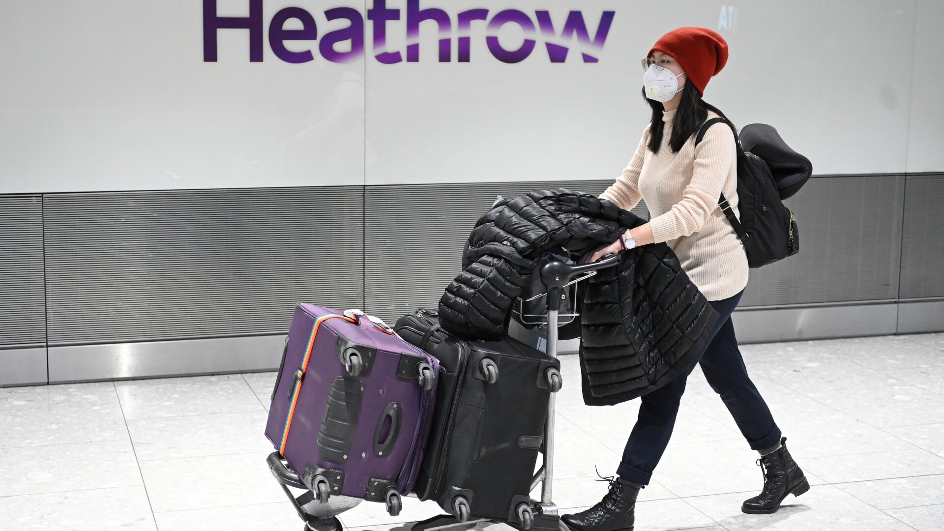 Passengers wear face masks as the push their luggage after arriving from a flight at Terminal 5 of London Heathrow Airport in west London on January 28, 2020.