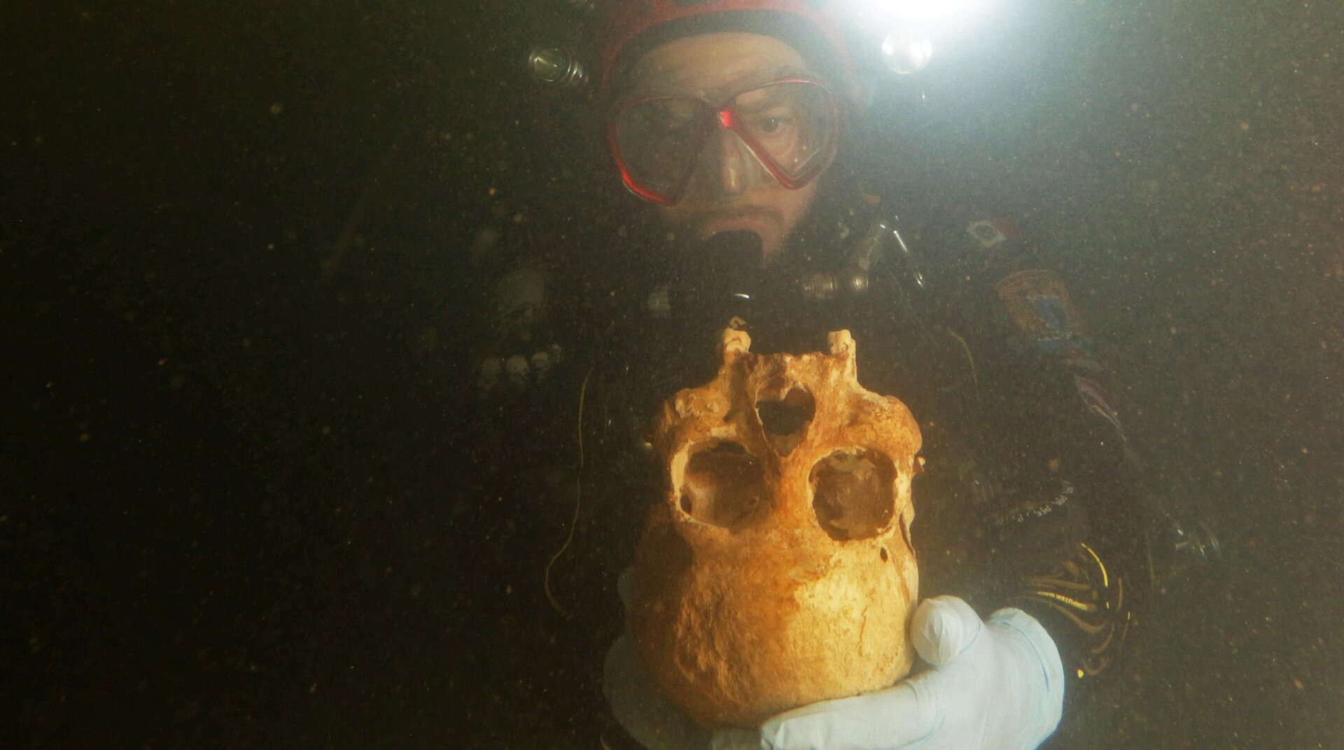 A cave diver holding a human skull in Chan Hol Cave.