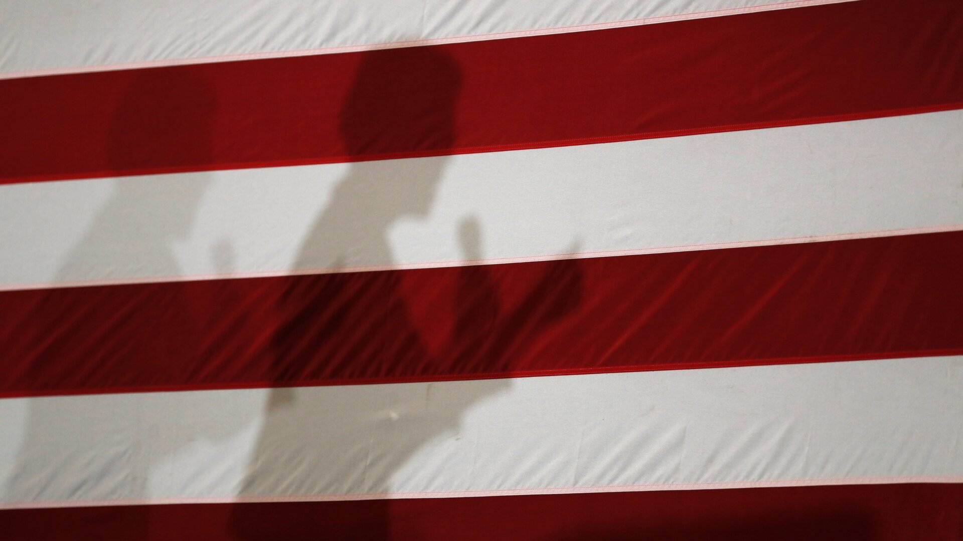 Elizabeth Warren’s shadow on a flag at Roosevelt High School in Des Moines, Iowa, in October 2019.