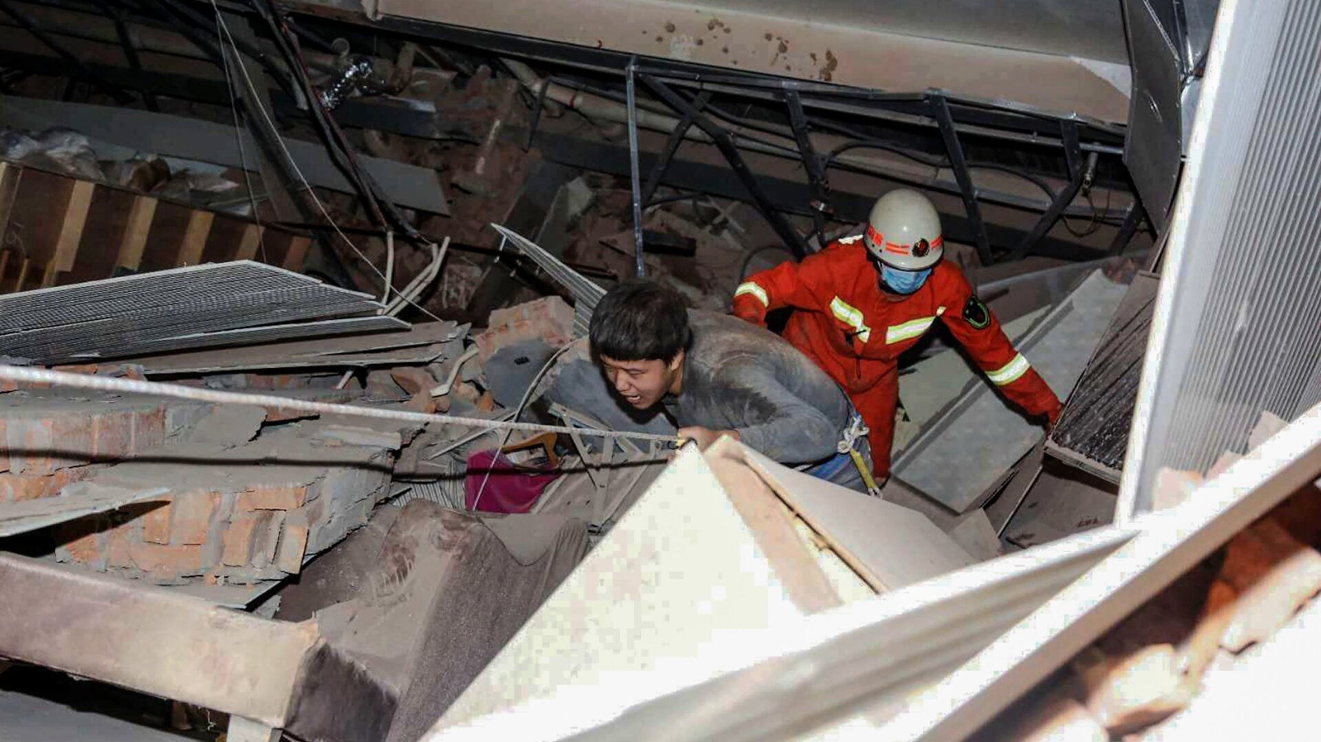 Rescuers help pull a man from the rubble after a hotel in Quanzhou, China inexplicably collapsed Saturday.