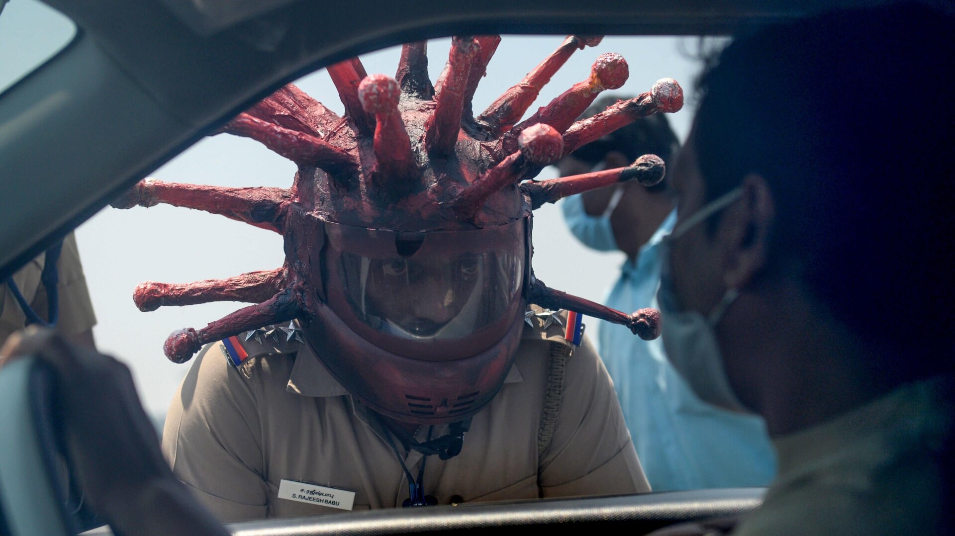 Police inspector Rajesh Babu wearing coronavirus-themed helmet speaks to a motorist at a checkpoint in Chennai on March 28, 2020.