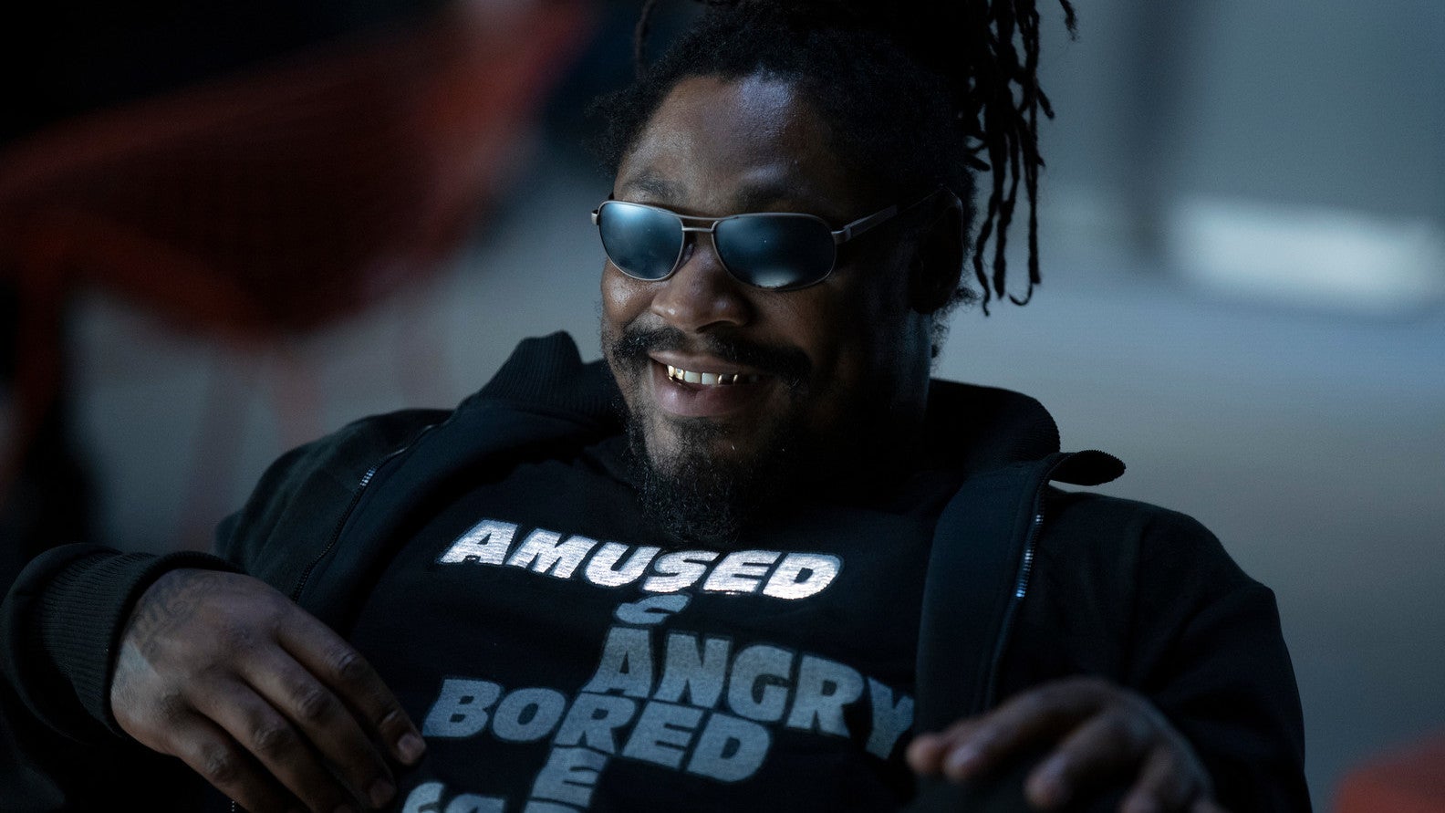 Marshawn Lynch in a scene from Westworld, wearing a t-shirt that changes highlighted words based on his mood. 