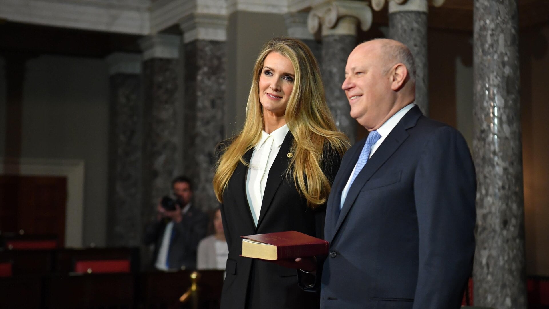 Sprecher stands with his wife, Senator Kelly Loeffler, who also sold stock long before the American public could foresee a crash.