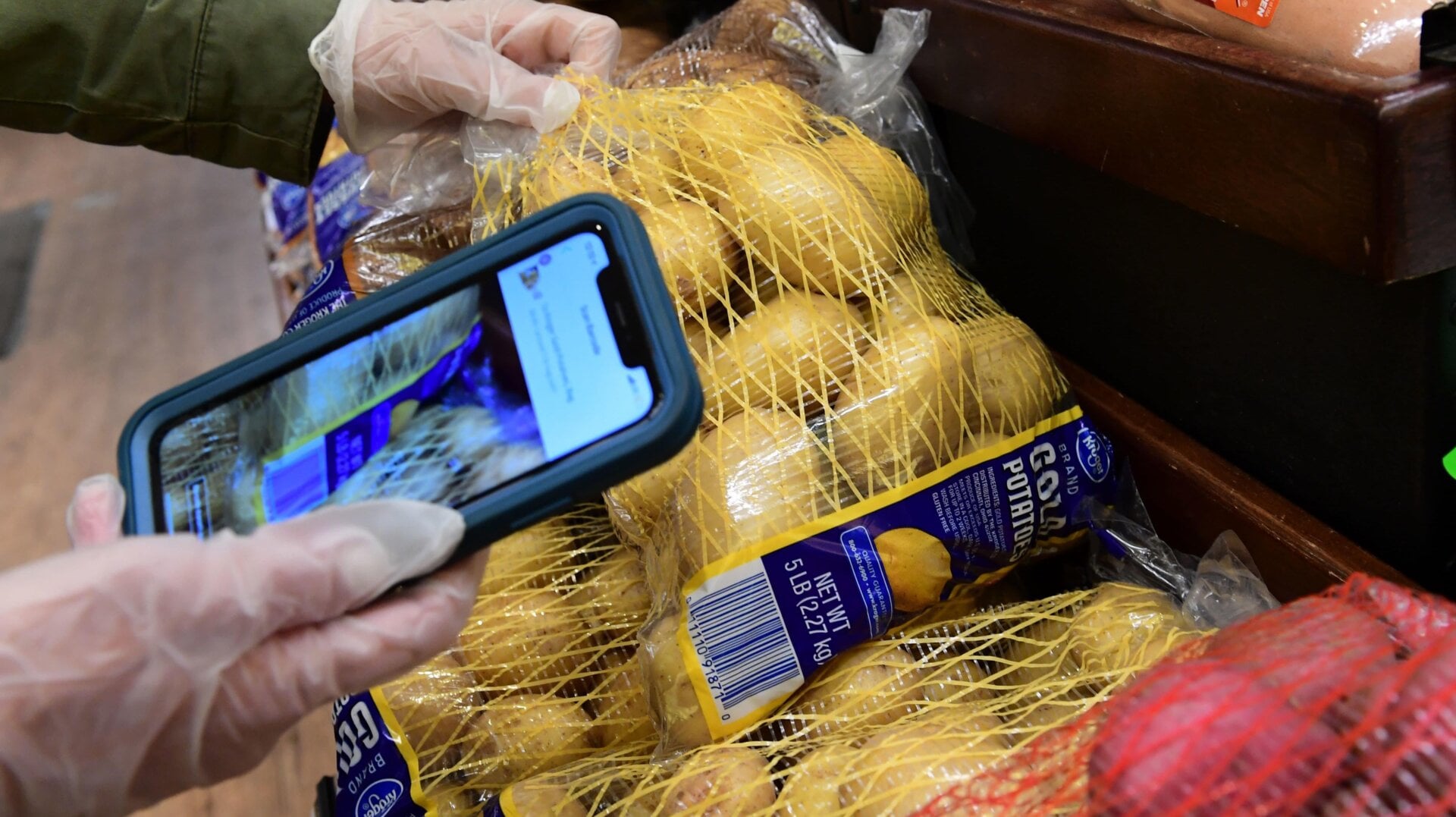 Instacart employee Monica Ortega uses her cellphone to scan barcodes showing proof of purchase for the customer while picking up groceries from a supermarket for delivery on March 19, 2020 in North Hollywood, California.