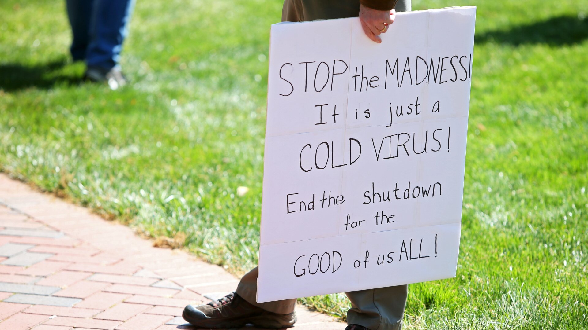 A man holding a sign incorrectly insisting the pandemic is just cold season in Virginia, April 16.