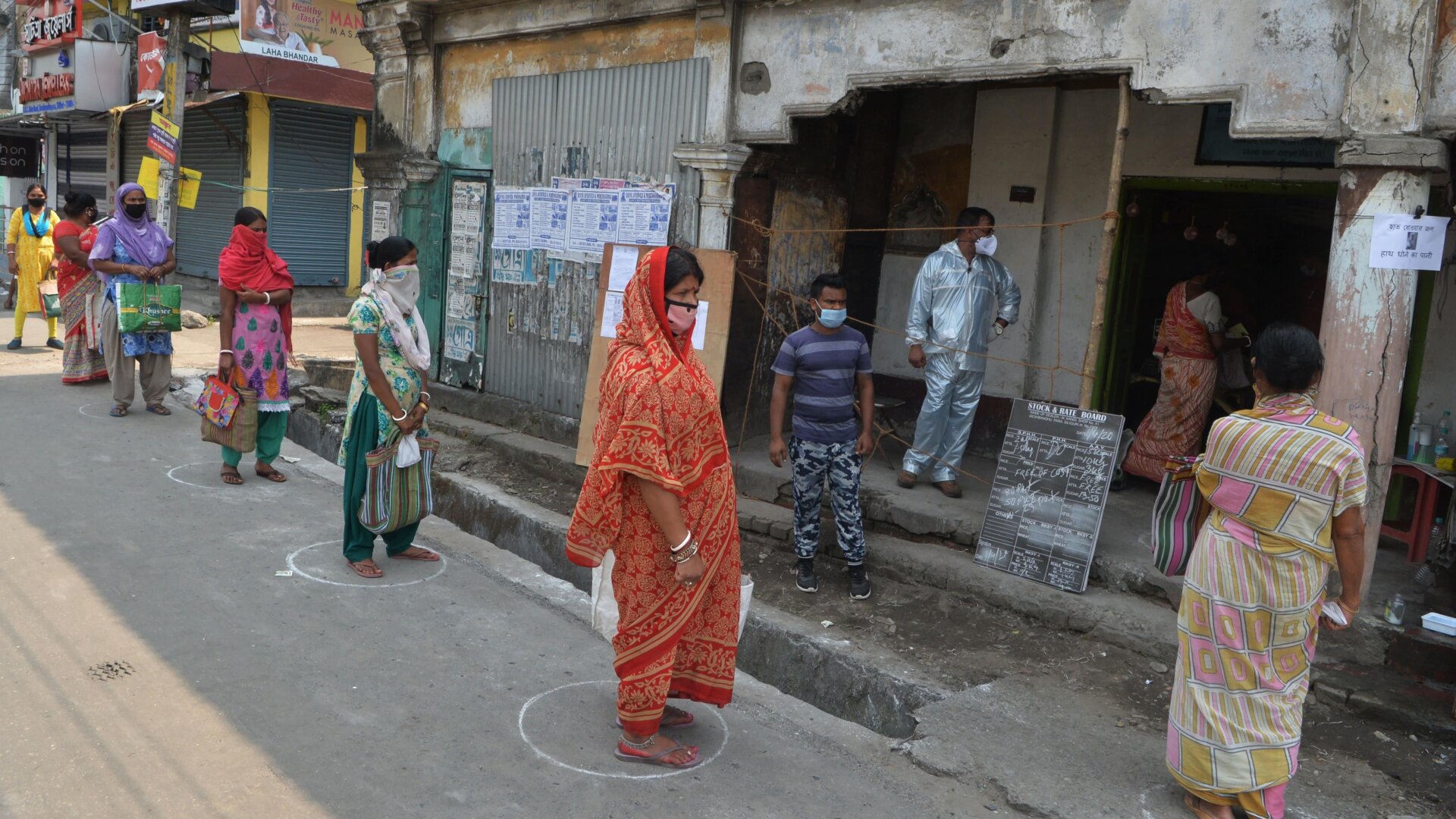Women queue on areas circles marked on the ground to maintain social distancing while waiting for rations at a government ration store during a government-imposed nationwide lockdown as a preventive measure against the COVID-19 coronavirus, in Siliguri on April 1, 2020.