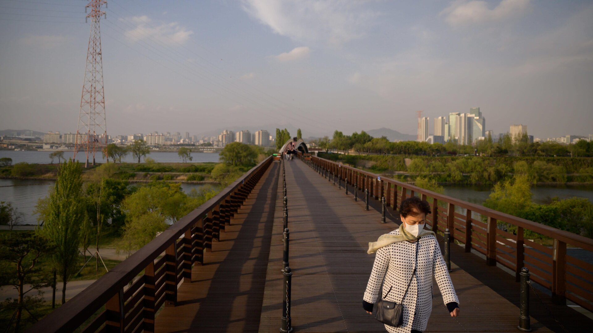 A woman walks along a bridge near the Yeouido district of Seoul, South Korea.