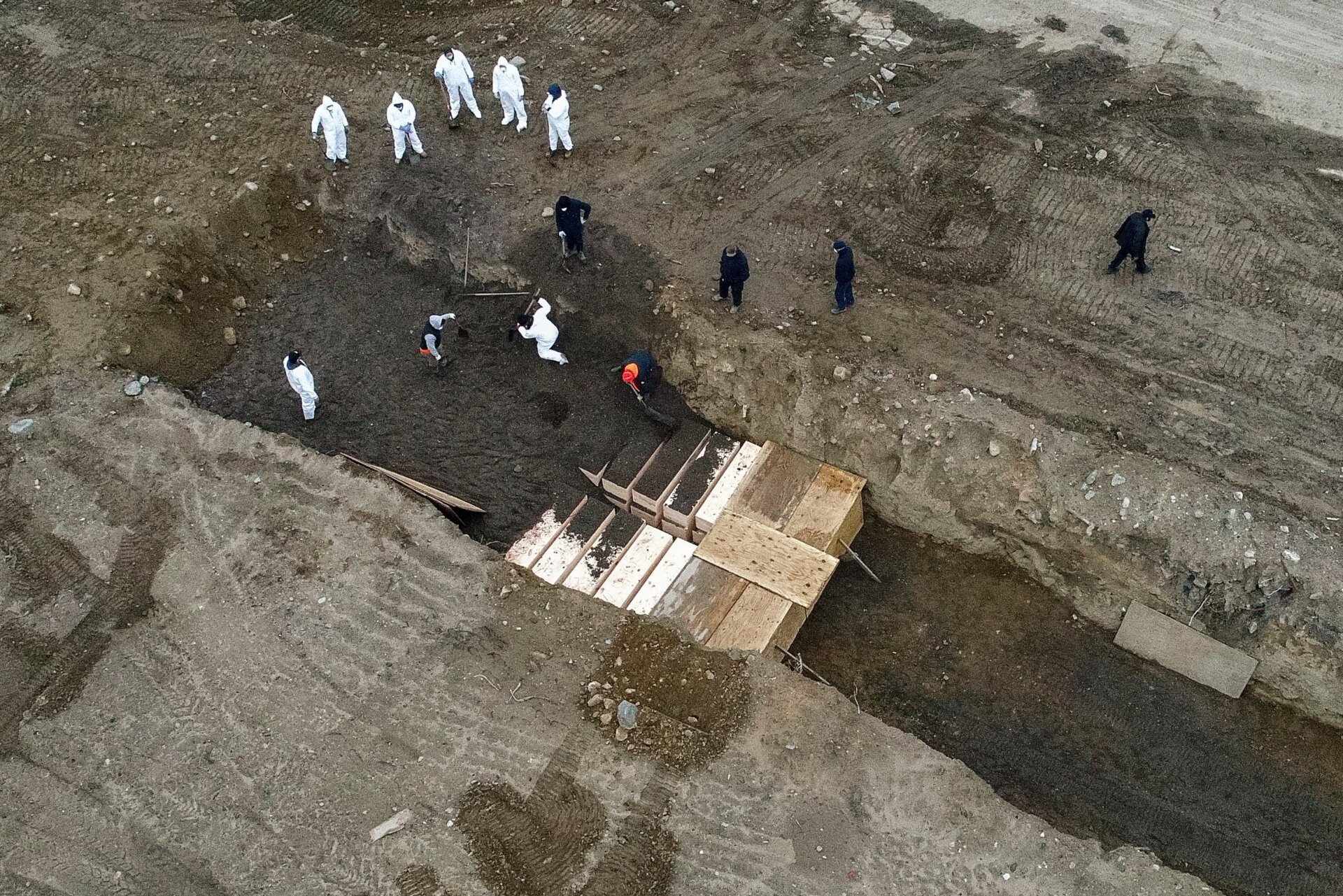 Workers wearing personal protective equipment bury bodies in a trench on Hart Island, just outside of the Bronx in New York on April 9, 2020.