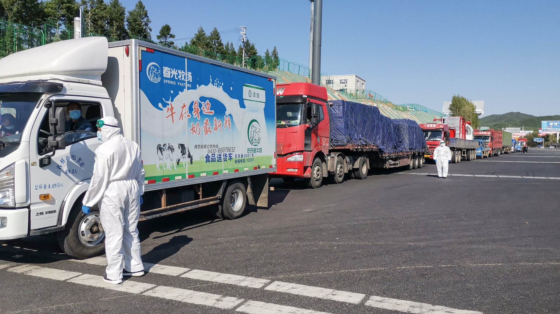 A staff member wearing protective gear speaks with a truck driver at an exit of a highway in Jilin in China’s Jilin province on May 13, 2020.