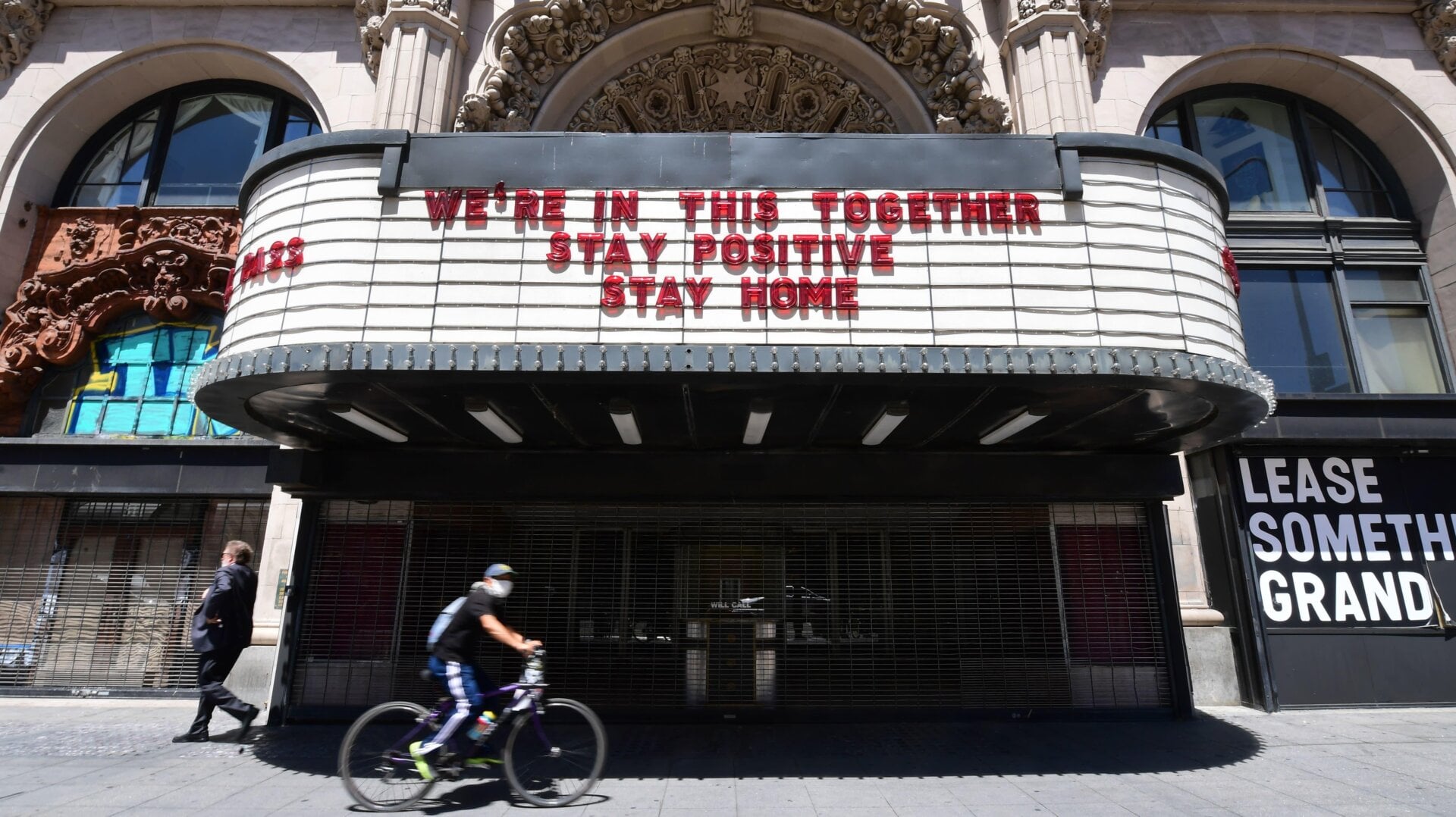 A cyclist wearing a face mask rides past the Million Dollar Theater, closed due to the coronavirus pandemic, in Los Angeles, California on May 4.