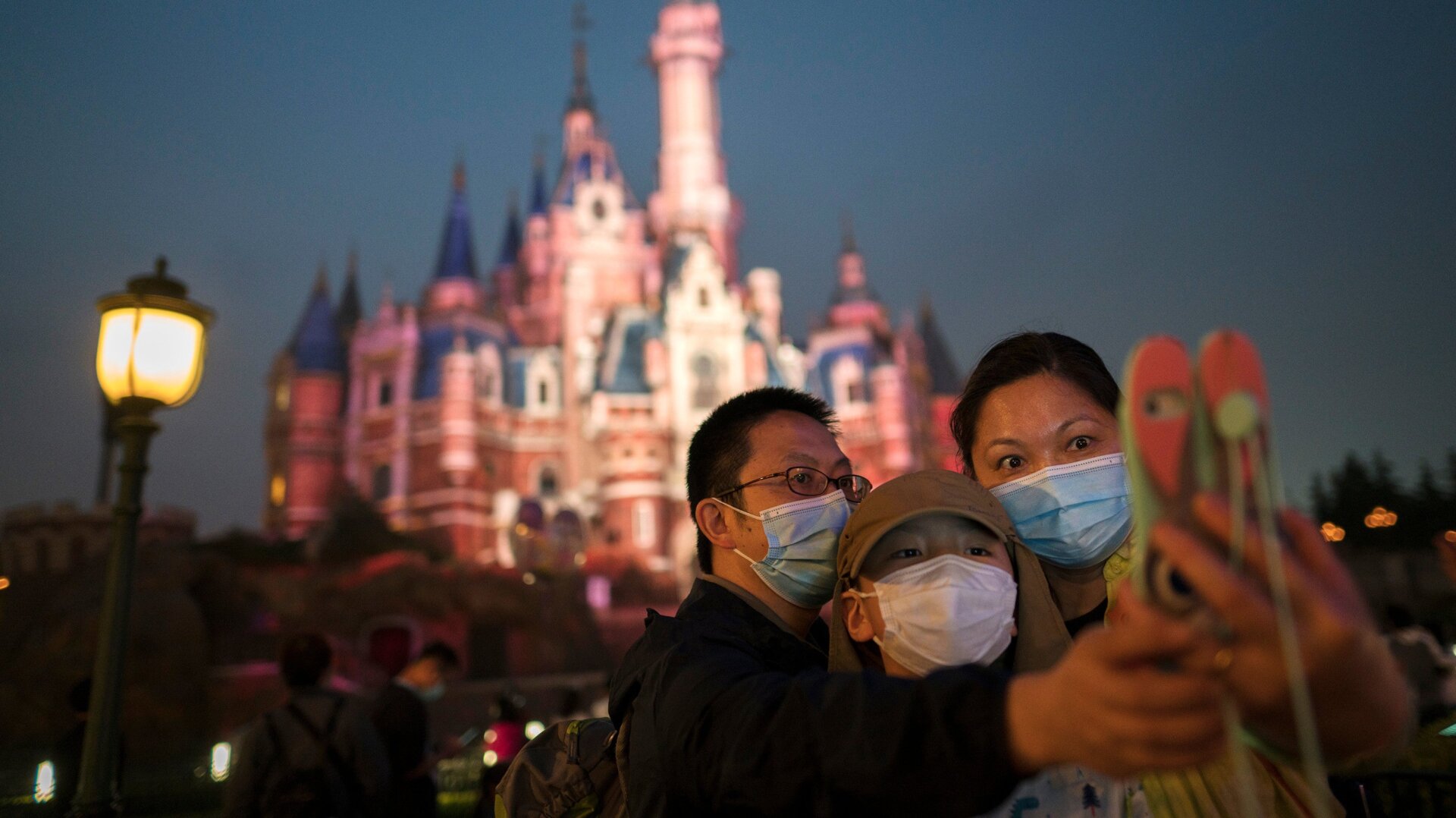 Guests take a photo in Shanghai Disneyland, a park where mask mandates have been largely successful.