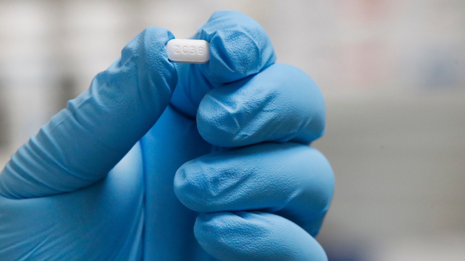 A pill of hydroxychloroquine being held by a pharmacy tech.