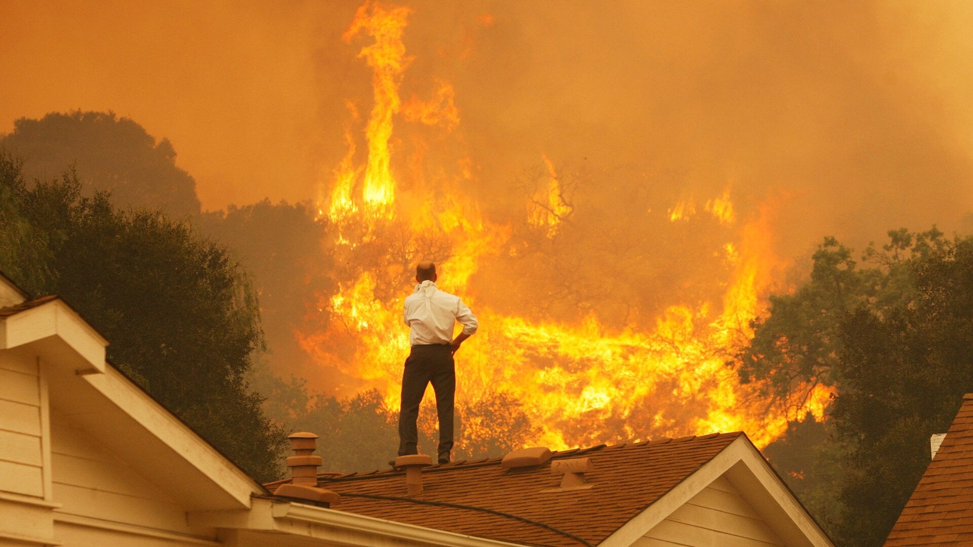 A man on a rooftop looks at approaching flames from the Springs fire in May 2013 near Camarillo, California.
