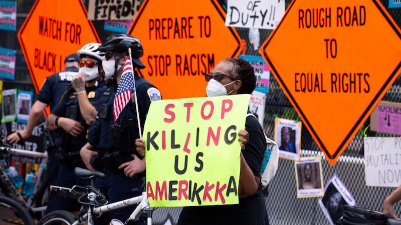 Washington, D.C. on July, 2020. A woman holds a sign in front of Lafayette Square near the White House.