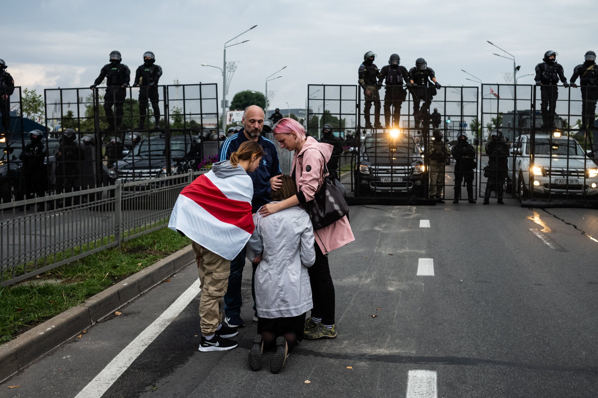 Protesters console a praying woman near riot police on Aug. 23, 2020, in Minsk, Belarus. 