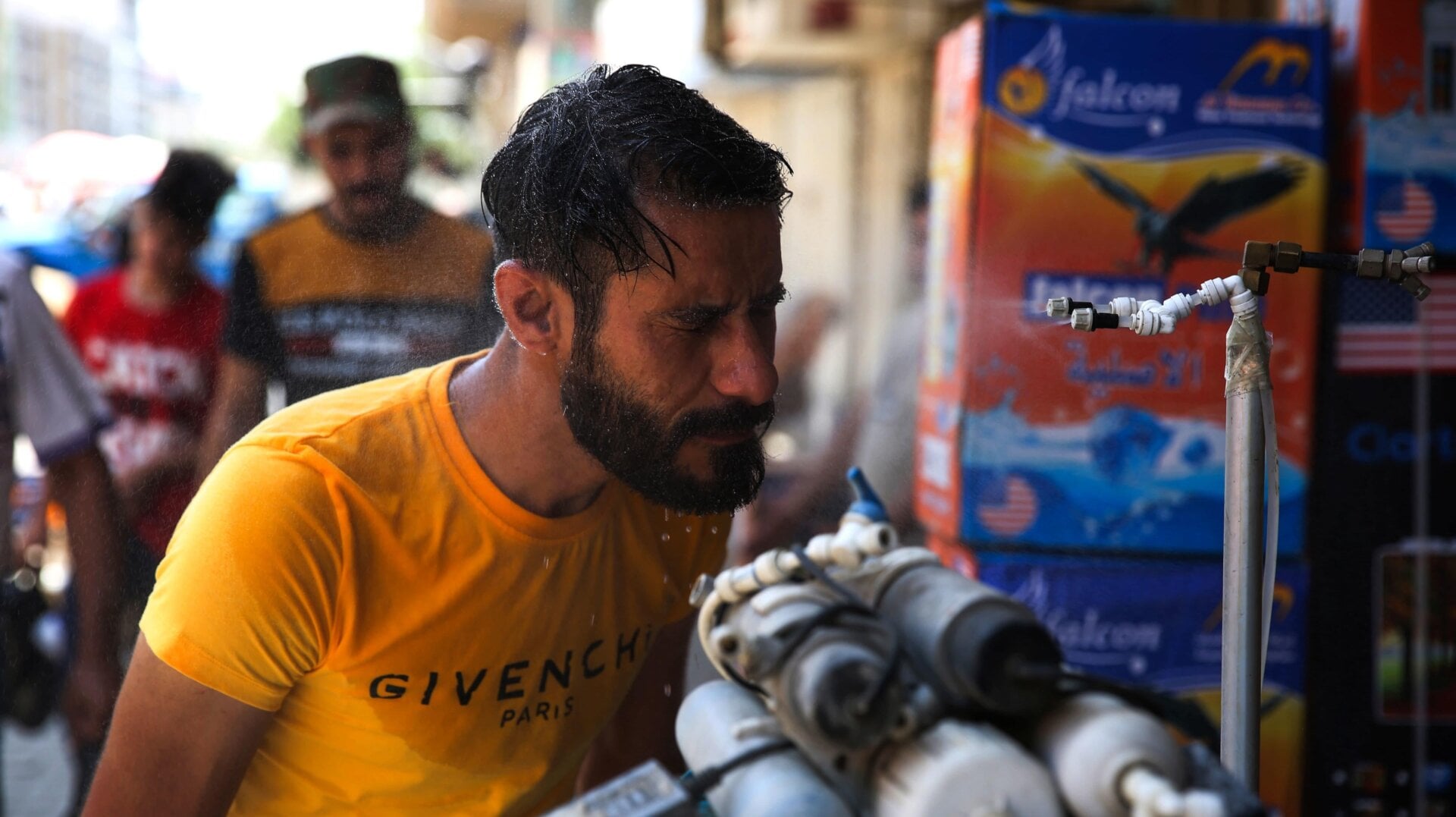 An Iraqi man uses a curbside shower to cool off during a heat wave in the capital Baghdad on June 14, 2019
