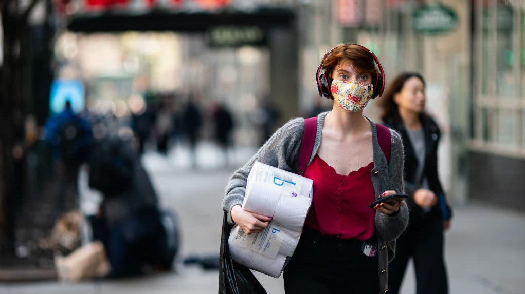 A woman wearing a protective mask carries a toilet paper package on the street on March 13, 2020, in New York City.