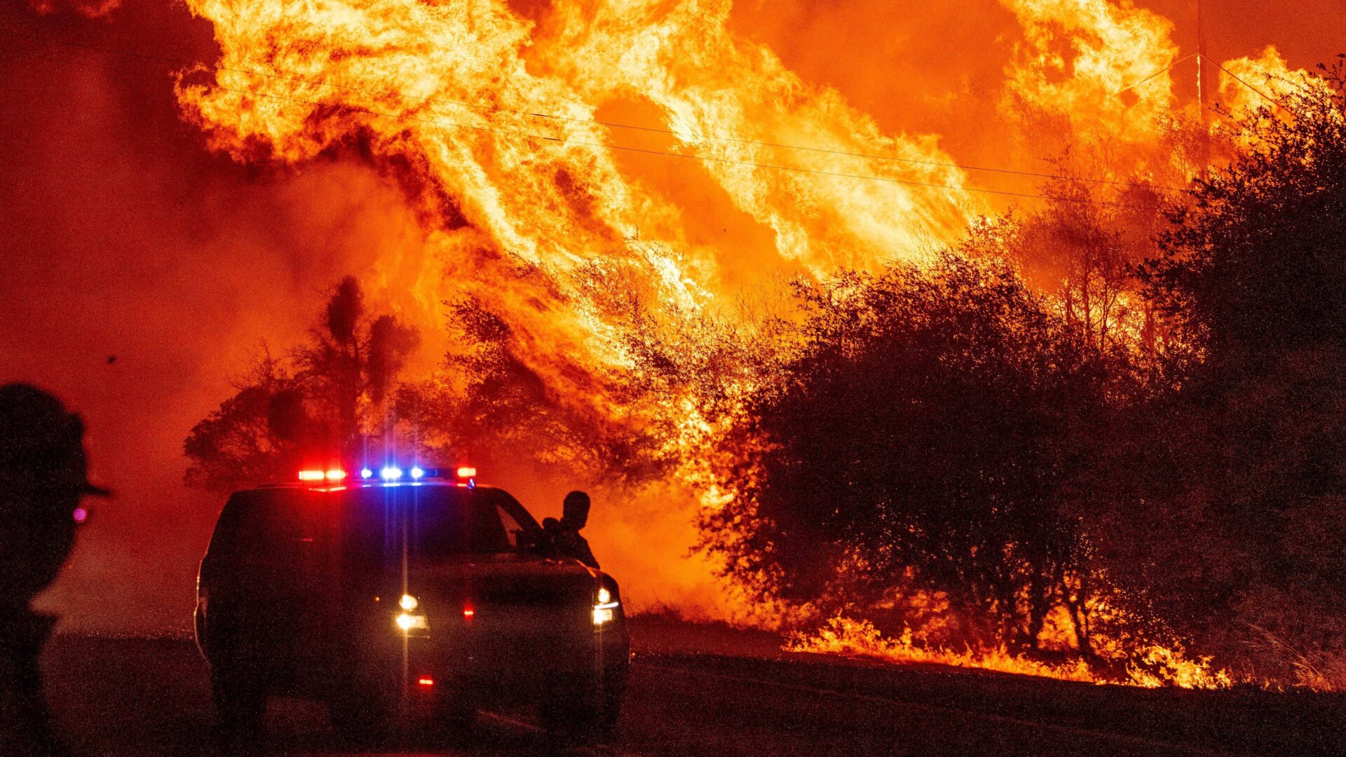A law enforcement officer watches flames launch into the air as fire continues to spread during the Bear fire in Oroville, California on September 9, 2020. Dangerous dry winds whipped up California’s record-breaking wildfires and ignited new blazes, as hundreds were evacuated by helicopter and tens of thousands were plunged into darkness by power outages across the western United States.