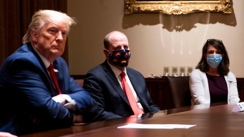 Colorado Governor Jared Polis (C) wears a face mask as U.S. President Donald Trump makes remarks during a meeting in the Cabinet Room of the White House, May 13, 2020.