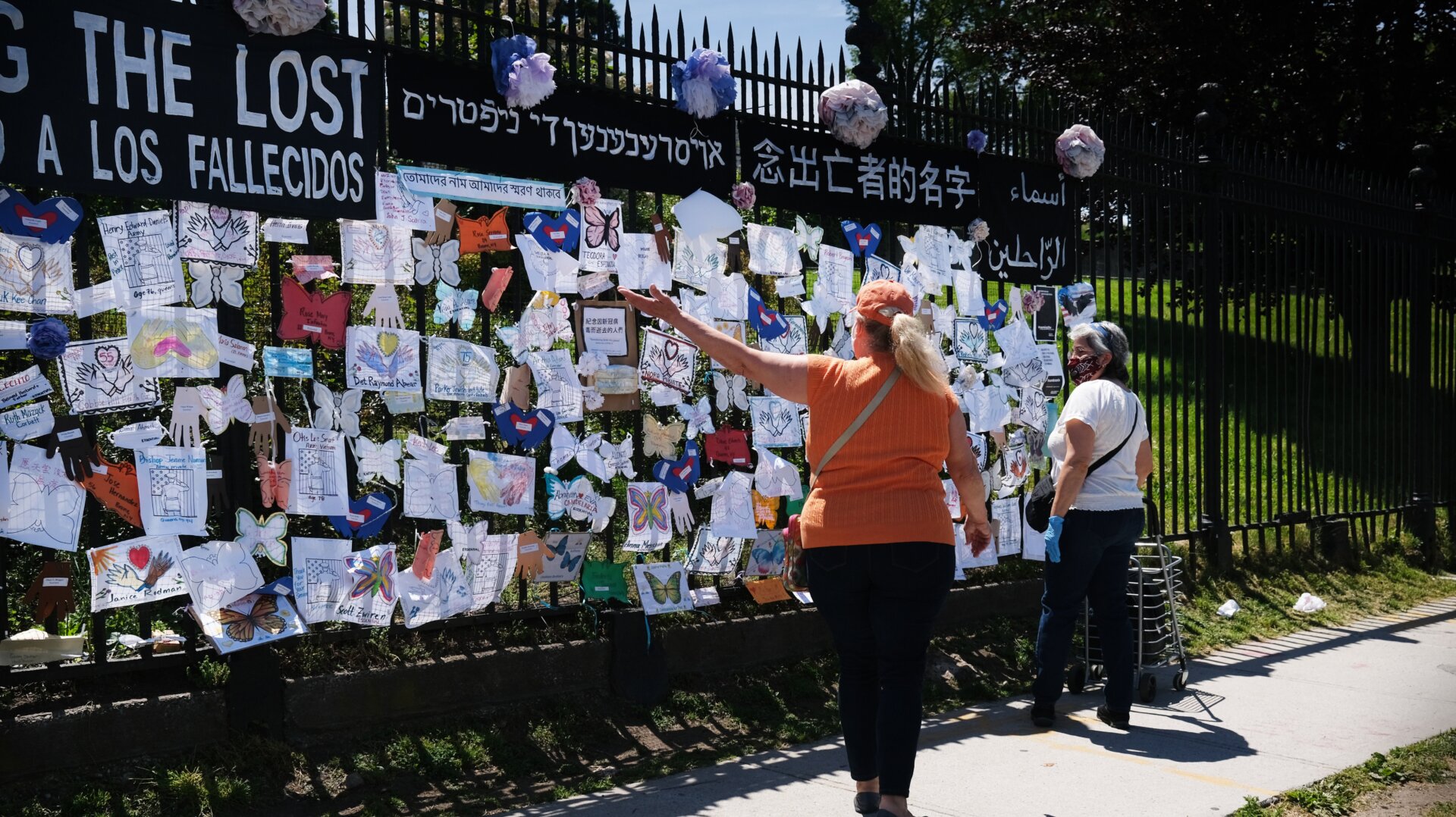 People walk by a memorial for those who have died from the coronavirus outside Green-Wood Cemetery on May 27, 2020.
