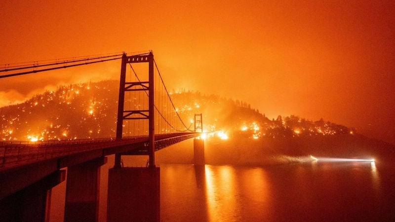 A boat motors by as the Bidwell Bar Bridge is surrounded by fire in Lake Oroville during the Bear Fire in Oroville, California on September 9, 2020.