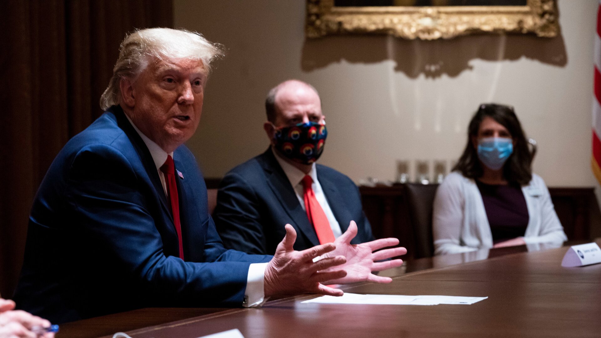 Colorado Governor Jared Polis (C) wears a face mask as U.S. President Donald Trump makes remarks during a meeting in the Cabinet Room of the White House, May 13, 2020.