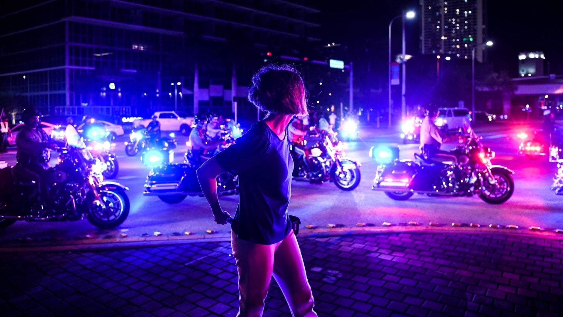 A woman looks at the Police convoy as Democratic presidential nominee and former Vice President Joe Biden arrives for an NBC townhall outside of the Perez Art Museum in Miami, Florida on October 5, 2020.