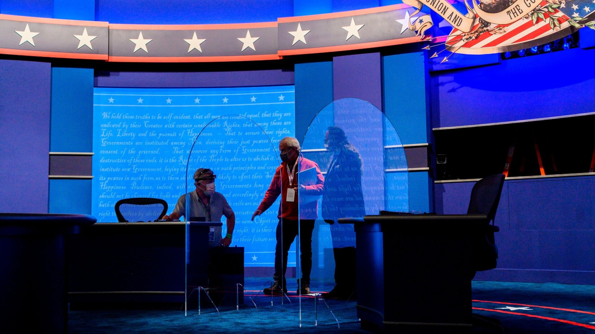 Workers install plexiglass protections between the debaters on the stage of the debate hall ahead of the vice presidential debate in Kingsbury Hall of the University of Utah October 6, 2020 in Salt Lake City, Utah.