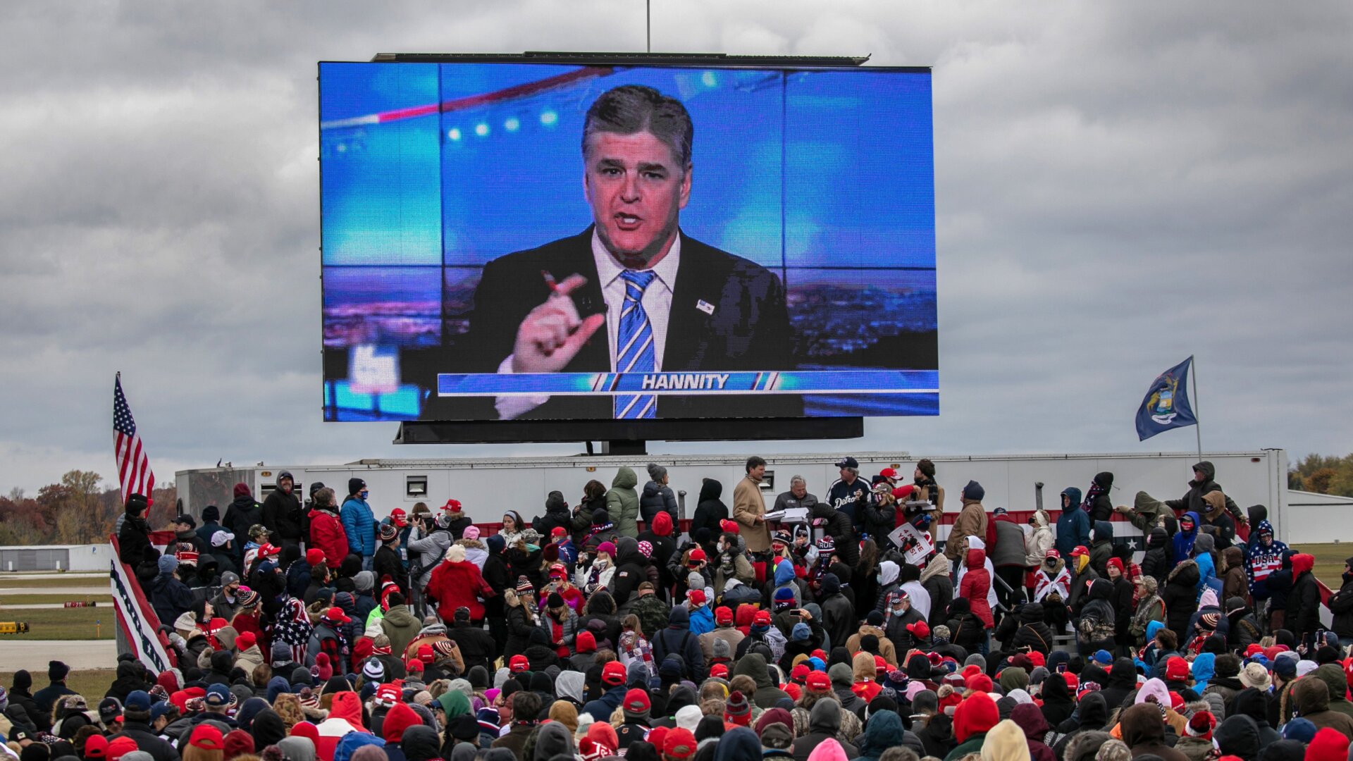 Supporters of U.S. President Donald Trump watch a video featuring Fox host Sean Hannity ahead of Trump’s arrival to a campaign rally at Oakland County International Airport on October 30, 2020 in Waterford, Michigan.