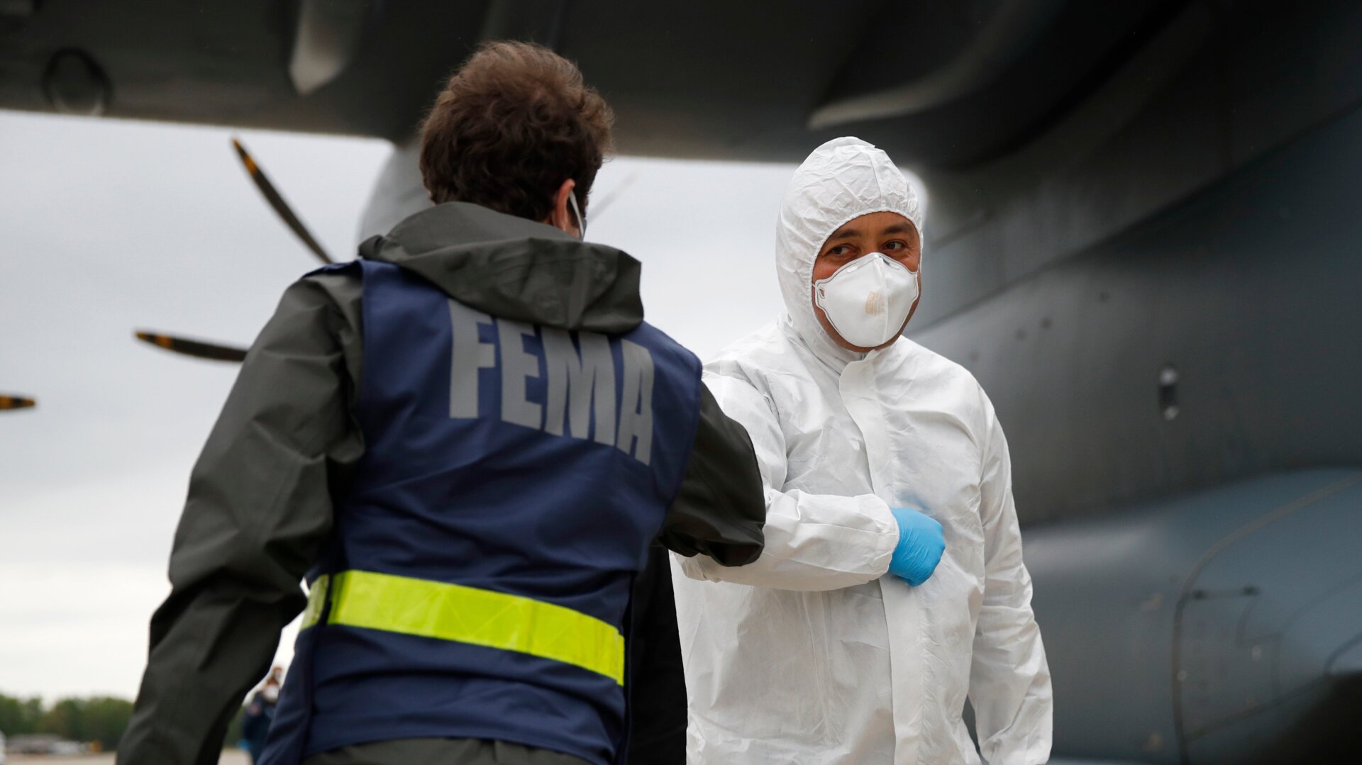 A  Turkish military flight crew member, right, bumps elbows with a FEMA worker as crews unload a donation of medical supplies from Turkey in April.