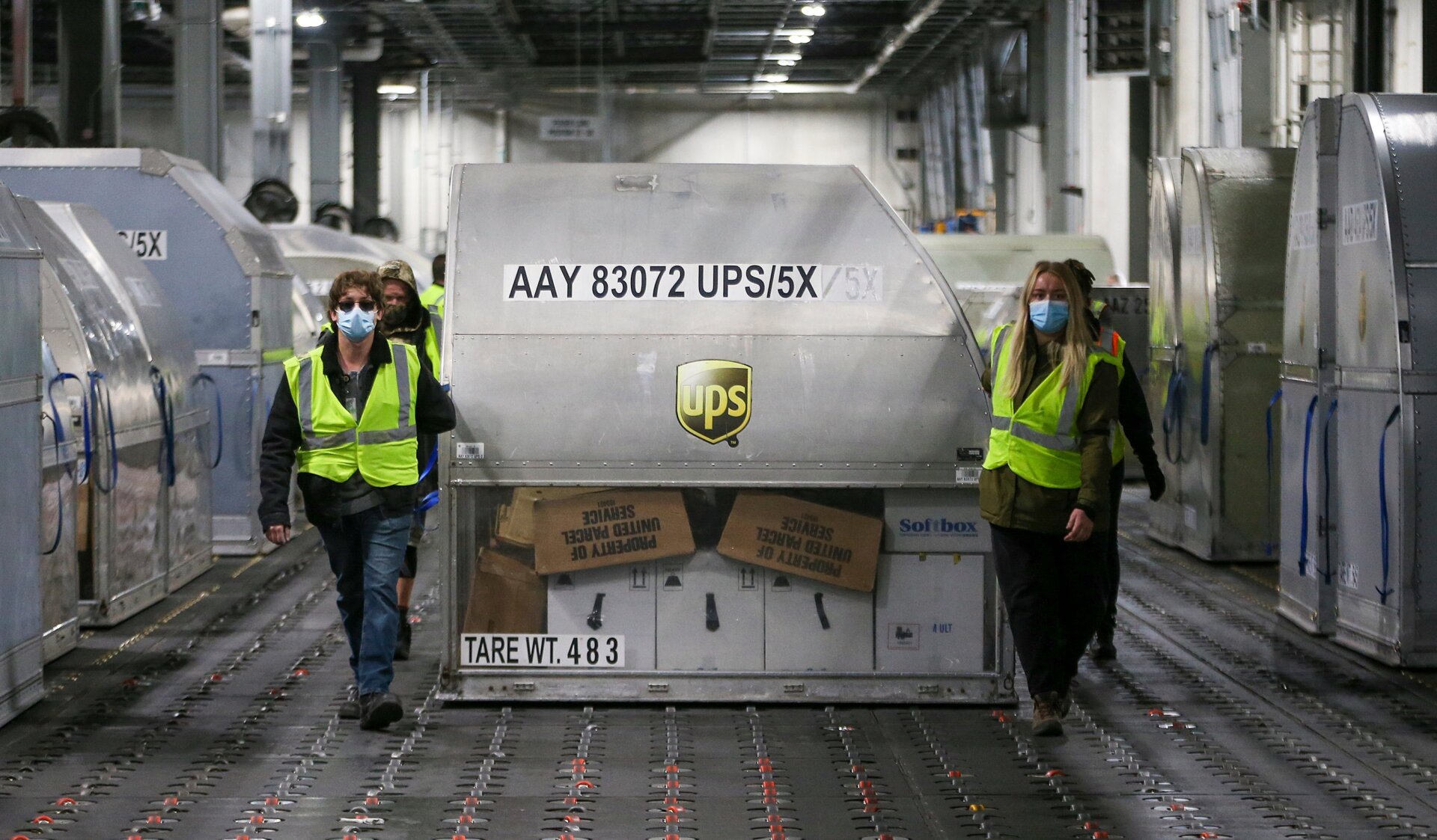 UPS employees move one of two shipping containers containing the first shipments of the Pfizer and BioNTech COVID-19 vaccine inside a sorting facility at UPS Worldport on December 13, 2020 in Louisville, Kentucky.