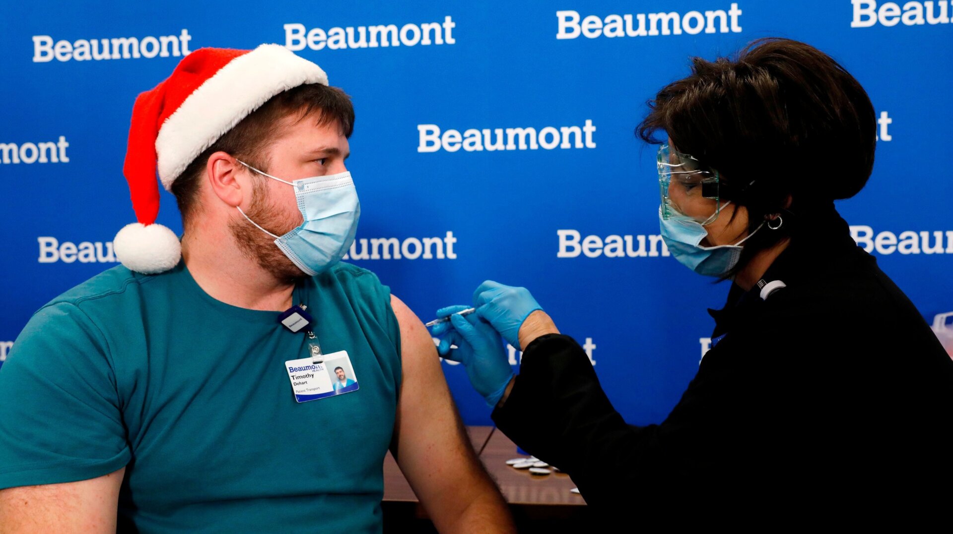 Beaumont Health Care worker Timothy Dehart (L) receives his first dose of the Pfizer/BioNTech covid-19 vaccine by Carolyn Wilson at their service center in Southfield, Michigan on December 15, 2020.