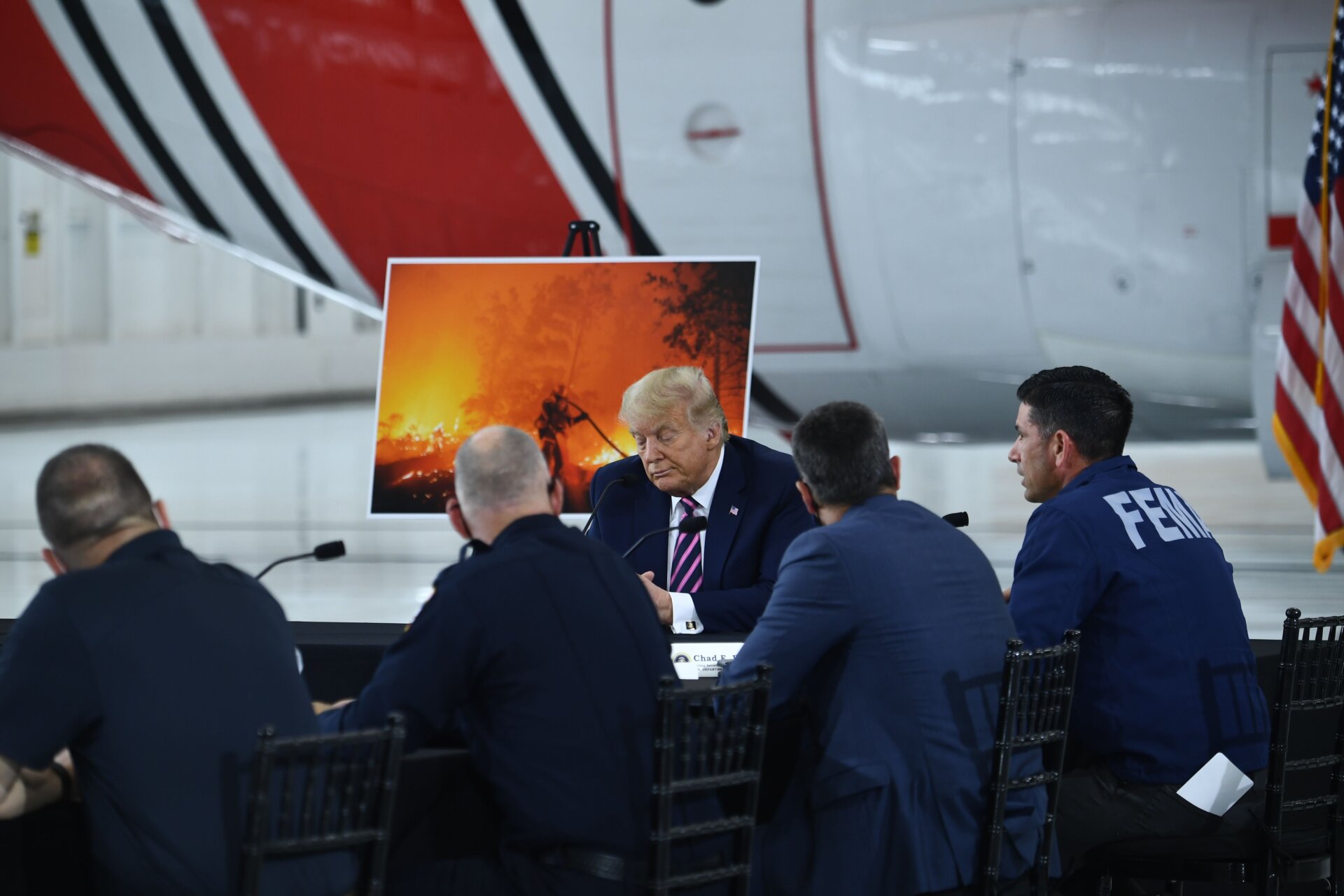 President Donald Trump listens as FEMA workers speak at Sacramento McClellan Airport in McClellan Park, California on Sept. 14, 2020 during a briefing on wildfires.
