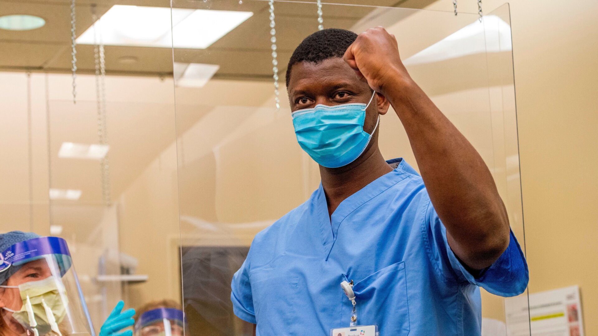 Lino Fernandes, an environmental services aide, celebrates after Nurse Susan McCarthy (L) gave him the very first vaccine shot to at Backus Hospital where 211 doses of the Pfizer/BioNTech covid-19 vaccine were delivered and being given to 30 hospital workers on the first day of vaccinations in Norwich, Connecticut on December 15, 2020.