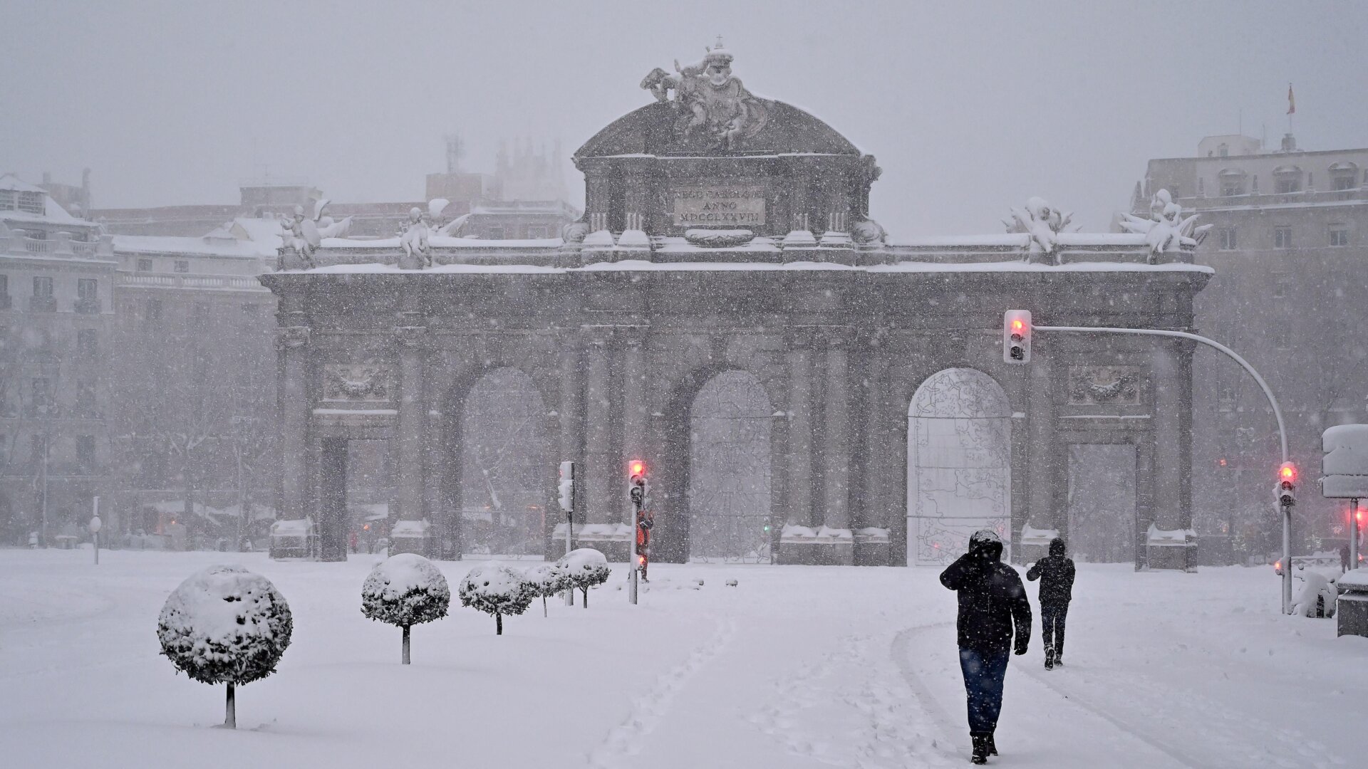 People walk amid a heavy snowfall in Madrid on January 9, 2021.