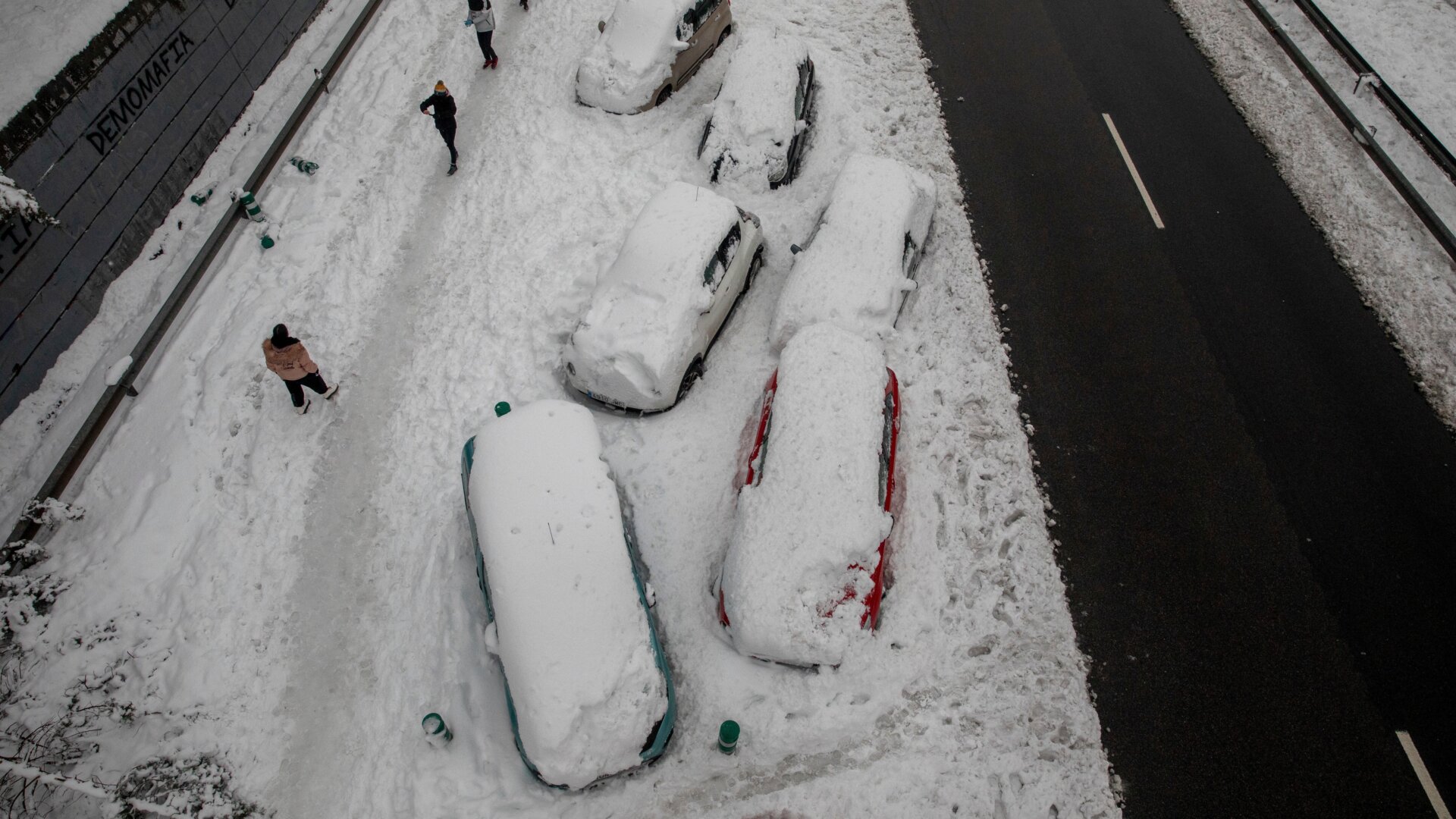 Cars are blocked on the snow as people walk past along the M-30 road during heavy snowfall on January 09, 2021 in Madrid, Spain. 
