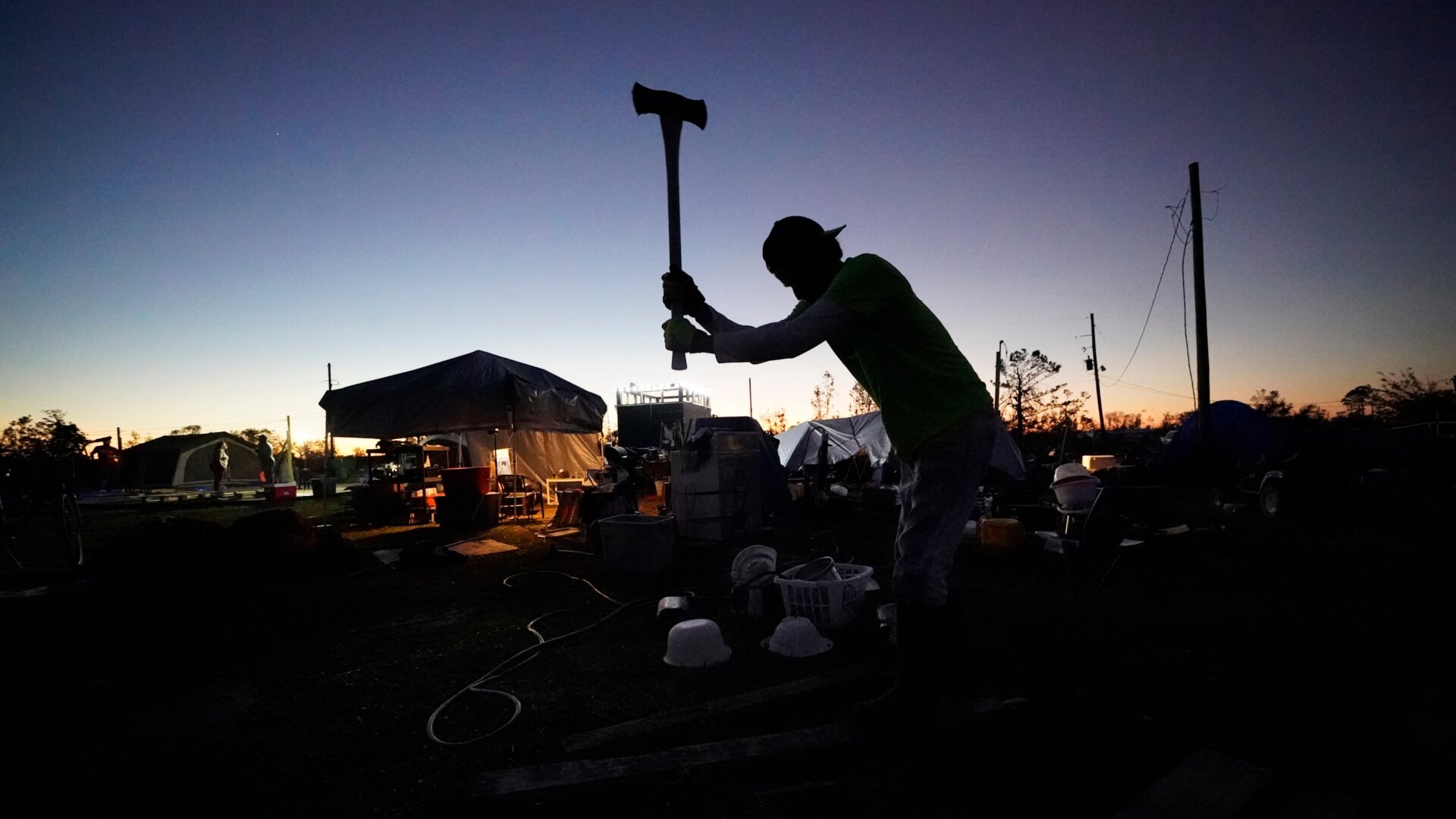 Ricky Trahan chops wood to make a fire on his property after their home was destroyed by both Hurricane Laura and Hurricane Delta in Lake Charles, Louisiana, Friday, Dec. 4, 2020. The city has been struck by calamity anew in this week's record cold.